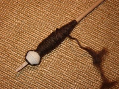Spindel mit weissem Tonwirtel und brauner Wolle