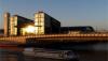 Der Berliner Hauptbahnhof im Sonnenuntergang mit der Spree im Vordergrund.