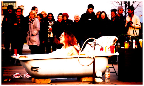 Frau in Badewanne vor Menschen Frau in Badewanne vor Menschen