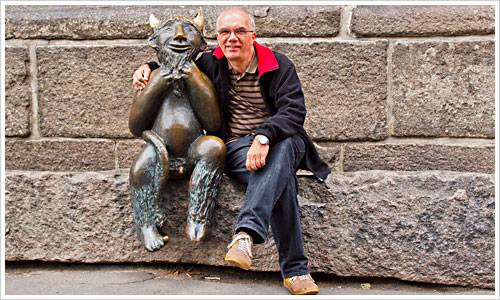 Ein Mann sitzt neben einer Figur des Teufels