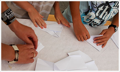 Kinder beim Falten von Papierfliegern Kinder beim Falten von Papierfliegern