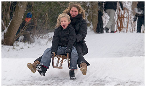Ein Schlitten mit zwei Personen springt über eine Schneekante