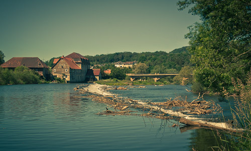 Fluss mit Wehr und Gebäuden
